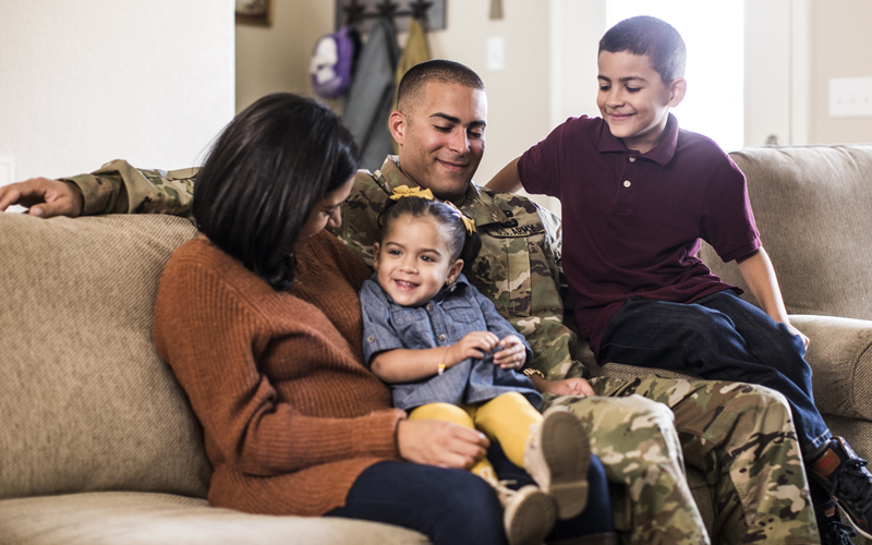 Soldier in uniform sitting on a couch with his wife, son, and daughter