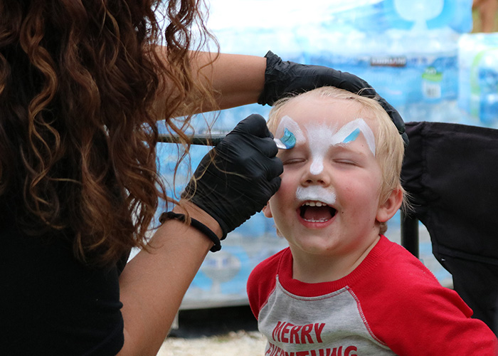 child happily getting face painted by childcare worker