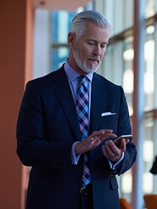 White man in business suit tapping his mobile phone