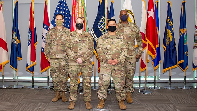 Four soldiers standing in front of flags